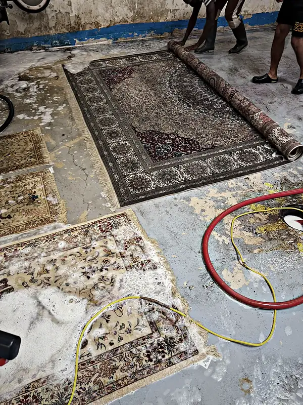 Tapis étendus au sol de l’atelier pendant le lavage à la main.
