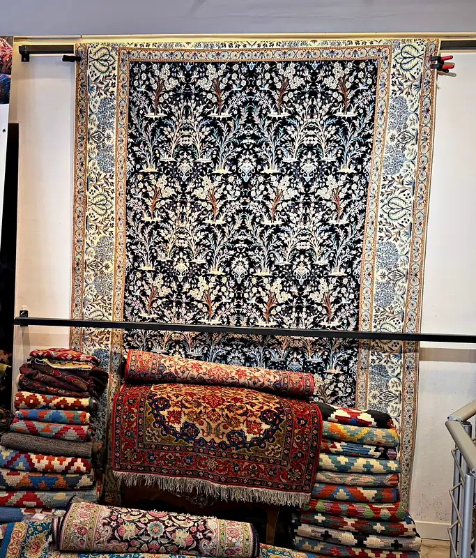 Tapis persan bleu nuit à décor d’arbre de vie, vu de face dans la boutique.