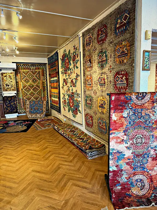 Intérieur de la boutique, parquet à chevrons et tapis aux murs.